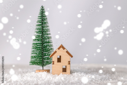 Model of a wooden house near a miniature Christmas tree © Anna