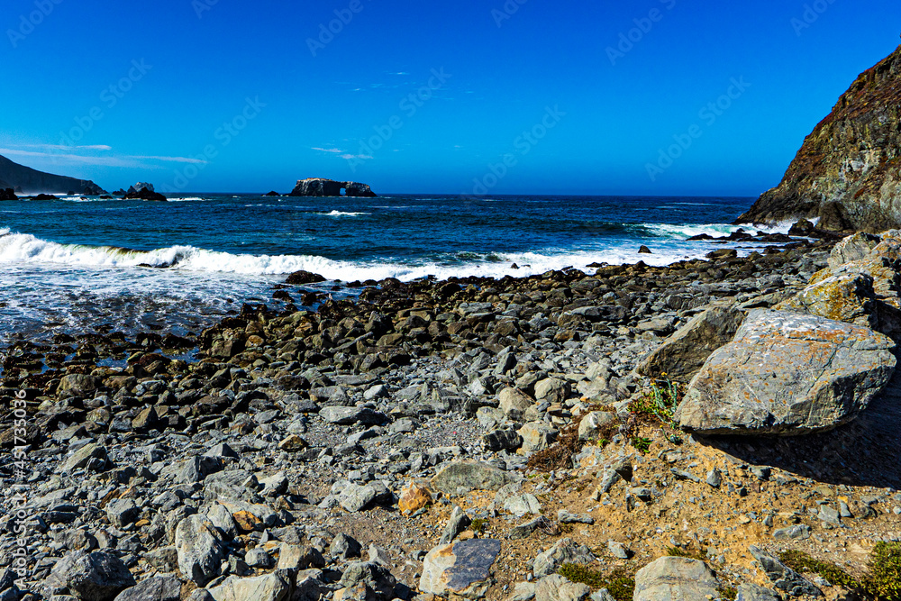 Looking out from a rocky beach to an arched rock on the California coast