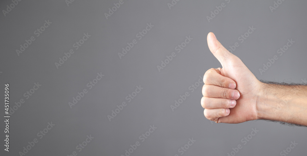 Male hand making a thumbs up gesture.
