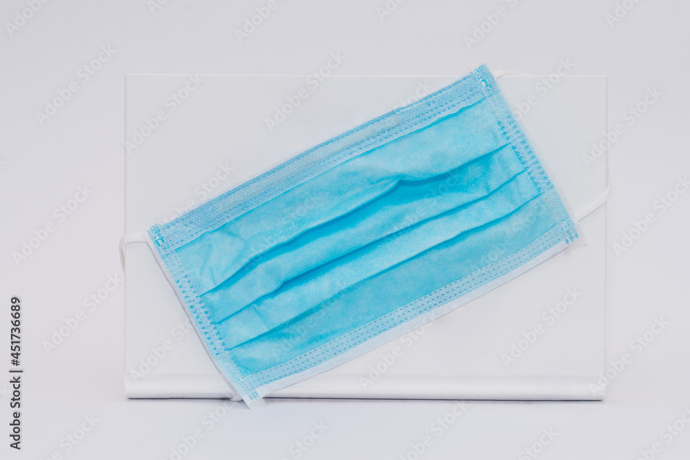 A medical mask worn on a book. Abstraction dangerous book. White book on a white background. A medical mask worn on a book. Abstraction dangerous book. White book on a white background.