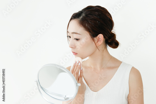 鏡を見ながらファンデーションを塗っている女性