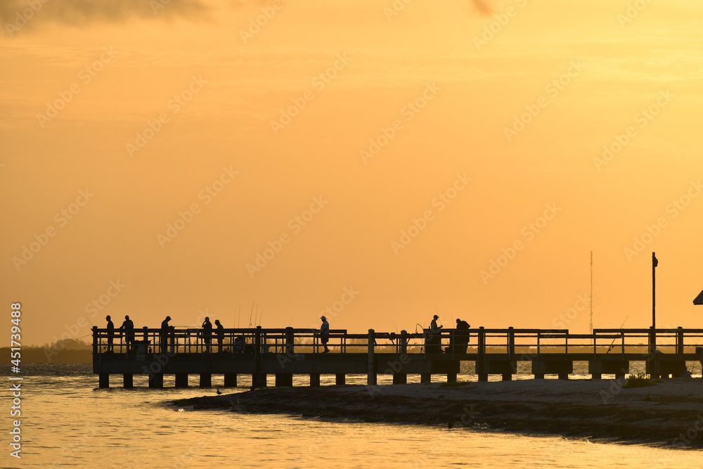 People fishing on a pier in Sanibel Island, Florida at sunrise.