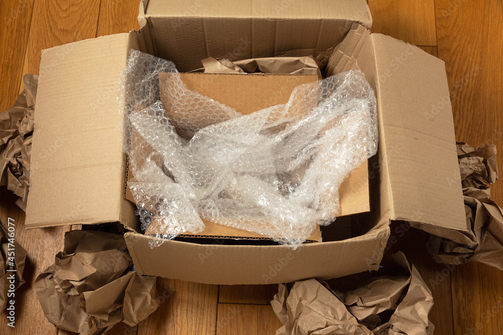 Cardboard boxes and crumpled wrapping paper with bubble wrap on the wooden  floor of the room foto de Stock | Adobe Stock