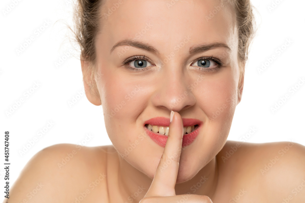 portrait of a happy blonde woman with a finger in front of her lips portrait of a happy blonde woman with a finger in front of her lips