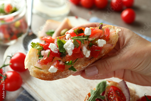 Female hand holds bruschetta, close up and selective focus