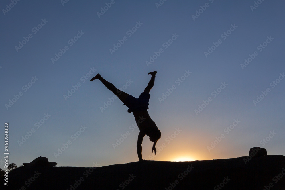 Boy doing acrobatics on a rock at sunset in autumn. Copy space. Backlight. Boy doing acrobatics on a rock at sunset in autumn. Copy space. Backlight.