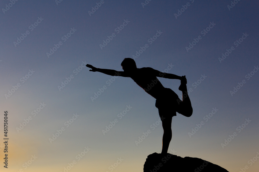 Silhouette of man practicing yoga at sunset on a rock in nature. Backlight. Copy space. Silhouette of man practicing yoga at sunset on a rock in nature. Backlight. Copy space.