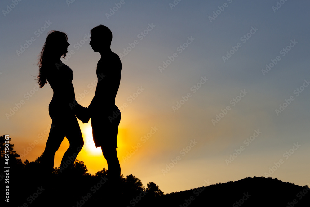 Loving couple holding hands in a romantic sunset on a lake. Autumn. Backlight. Copy space.