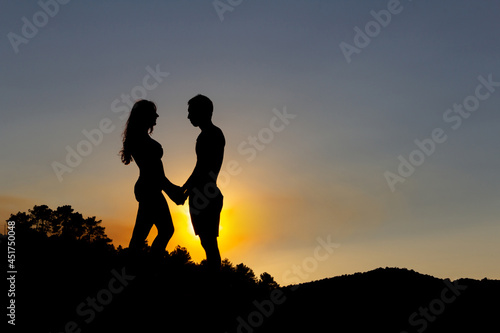 Loving couple holding hands in a romantic sunset on a lake. Autumn. Backlight. Copy space.