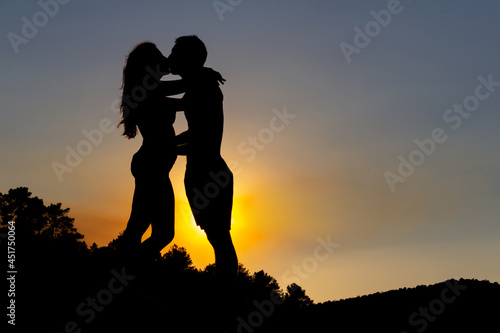 Couple in love kissing in a romantic sunset on a lake. Autumn. Backlight. Copy space.