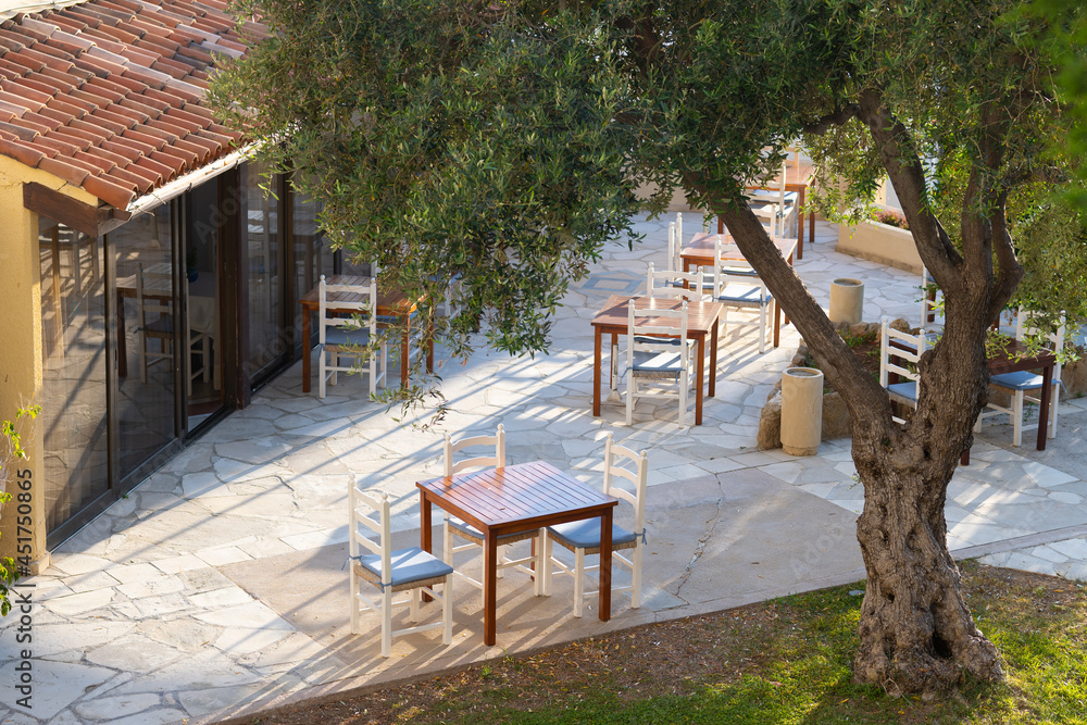 Cute empty cafe in Cyprus in courtyard with tree and empty tables