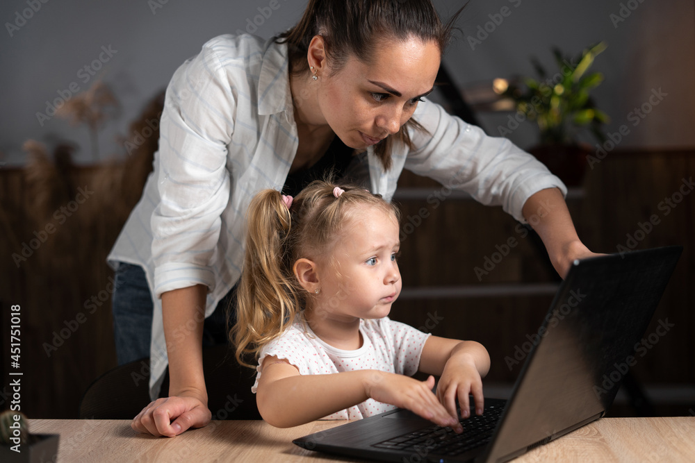 Happy cute little girl using laptop learning to use internet with mom supervision at home, adult mother and little daughter having fun, playing game, Happy cute little girl using laptop learning to use internet with mom supervision at home, adult mother and little daughter having fun, playing game,