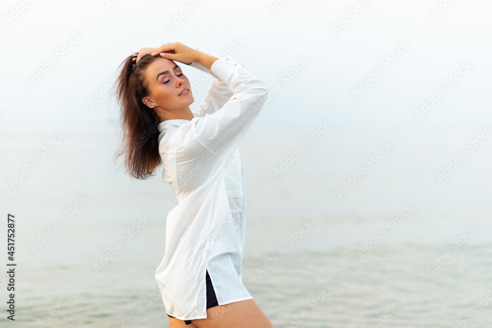 Young pretty fashion girl in white shirt. vacation at sea.Romantic Young Woman on Blue Natural summer Background. Young pretty fashion girl in white shirt. vacation at sea.Romantic Young Woman on Blue Natural summer Background.