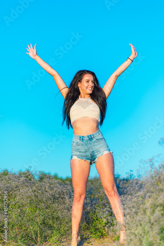 Joyful young girl raised his hands up and smiles. Happiness in lifestyle.woman raising her hands up in the blue air.