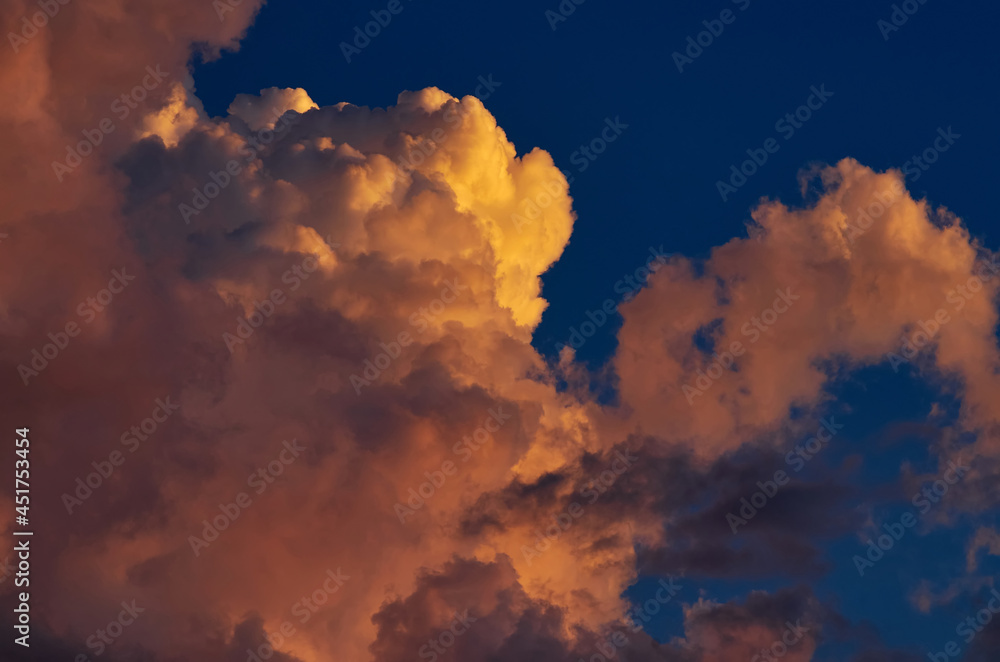 Fluffy clouds tinted orange by the sunset