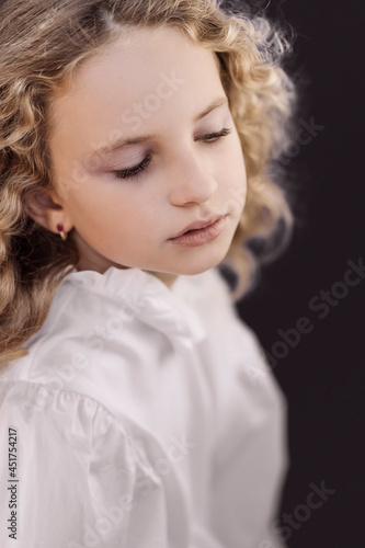 Emotional portrait of young beautiful girl with curly hair. Female model studio shot against black background. Hight quality photo. 