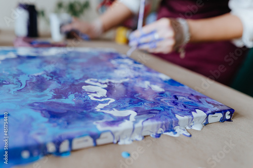 Artist mixing acryl paints on the picture working in fluid art technique