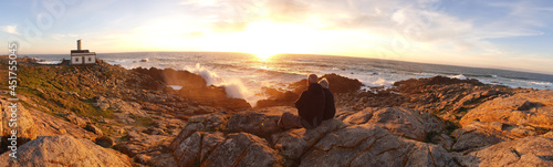 pareja observando la puesta de sol en  el faro de corrubedo en galicia photo