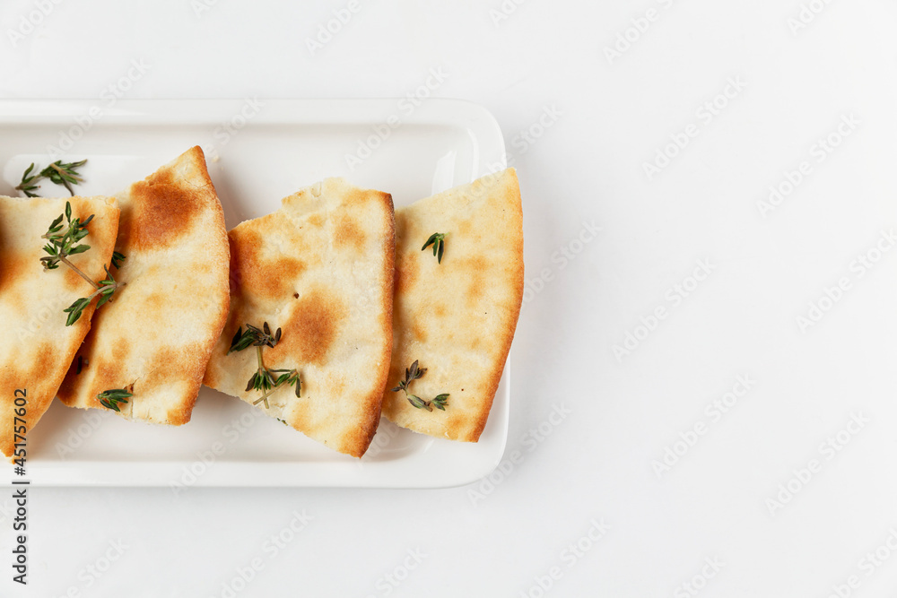 Traditional Italian bread with rosemary. Appetizing slices on a white plate. White background. Space for text. Close-up. Traditional Italian bread with rosemary. Appetizing slices on a white plate. White background. Space for text. Close-up.