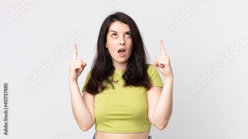 Φωτογραφία pretty woman looking shocked, amazed and open mouthed, pointing upwards with bot