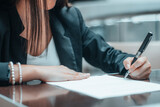 Mujer joven firma en un papel un contrato de trabajo junto a su ordenador
