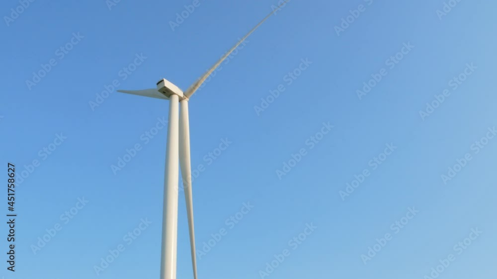 Wind turbine rotating on clear blue sky background. Local eco friendly powerful converter farm generating clean renewable wind energy. Green electricity ecological background farming screensaver 4K Wind turbine rotating on clear blue sky background. Local eco friendly powerful converter farm generating clean renewable wind energy. Green electricity ecological background farming screensaver 4K