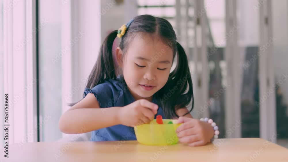 Girls use a fork to dip jelly into their mouths. Asian children are happily eating desserts. Normal angle shot Hand-held 4k slow-motion footage Girls use a fork to dip jelly into their mouths. Asian children are happily eating desserts. Normal angle shot Hand-held 4k slow-motion footage