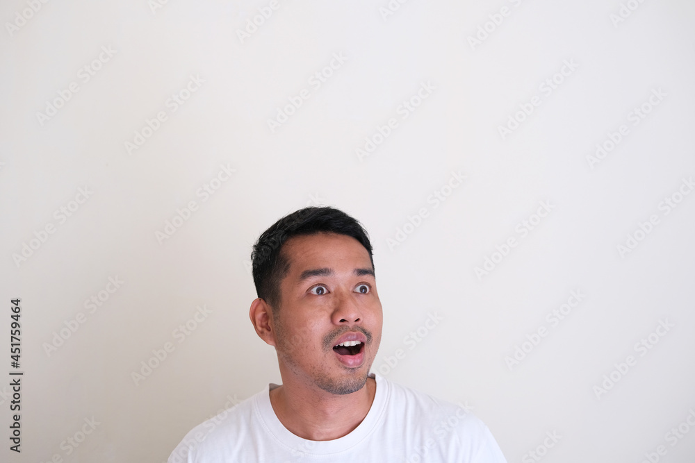 Funny Asian man showing amazed expression while looking to his side. Copy space Funny Asian man showing amazed expression while looking to his side. Copy space
