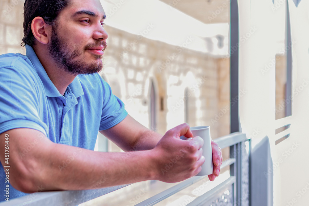 Fototapeta premium Side view of a happy man contemplating views with coffee cup on a balcony.
