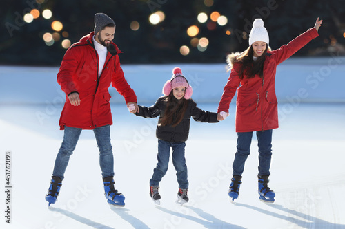 Papier peint Happy family spending time together at outdoor ice skating rink
