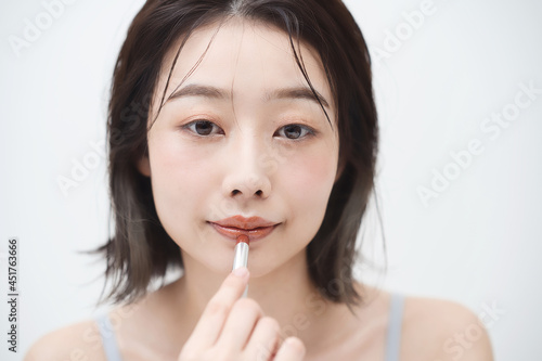 口紅を唇に塗る若い女性