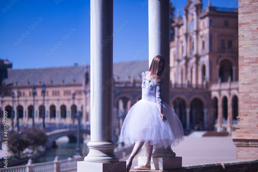 Obraz premium Adult female Hispanic classical ballet dancer making figures between two stone columns, wearing a white tutu.