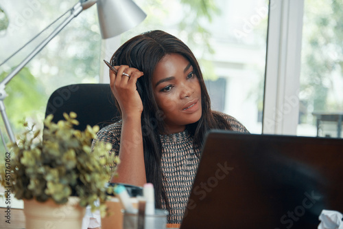 Free Download Female head of digital marketing department scratching her head when reading contract details on laptop screen - GFXLoad
