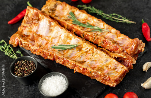 raw pork ribs marinated with spices on a stone background