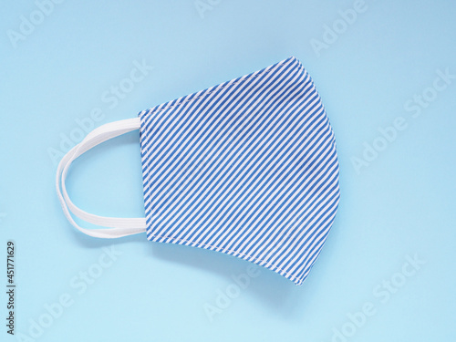 Top view, Fabric face mask blue-white stripes to prevention pollution and viruses. DIY handmade from cotton muslin on blue background. Healthcare, Medical and New normal concept. Copy space.