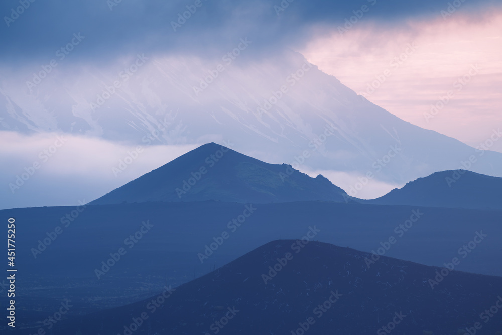 Tolbachik volcano with clouds at sunrise. Volcano craters and black lava fields. Kamchatka peninsula, Russia.