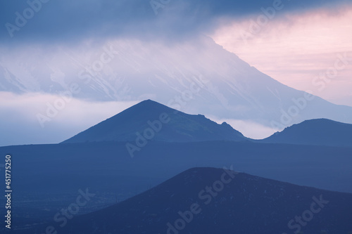 Tolbachik volcano with clouds at sunrise. Volcano craters and black lava fields. Kamchatka peninsula, Russia.