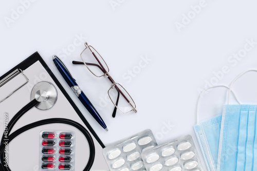 Flatlay composition with glasses, pen, pills, and stethoscope. Doctor's workspace. Medical concept. Top view. Place for text.