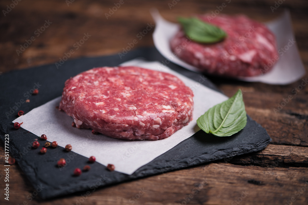 Raw ground beef meat burger steak cutlets on wooden background Raw ground beef meat burger steak cutlets on wooden background