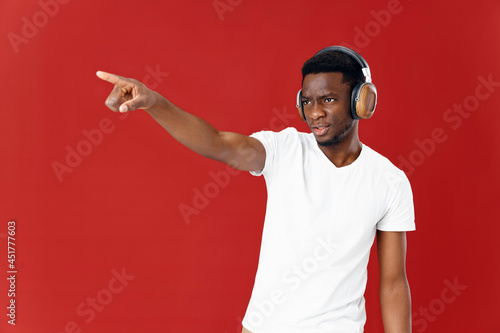 man of African appearance in headphones red background Copy Space