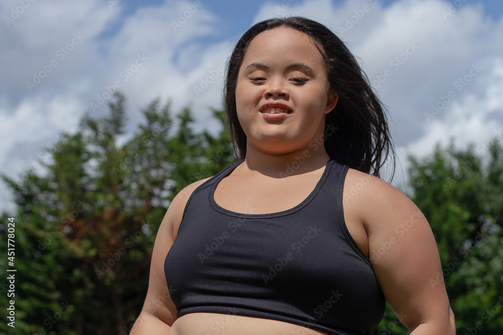 Portrait of young biracial woman with Down Syndrome in active wear smiling Portrait of young biracial woman with Down Syndrome in active wear smiling