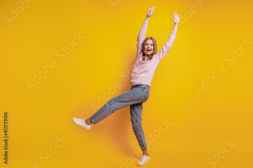 Photo of positive girl stand one leg have fun on yellow background
