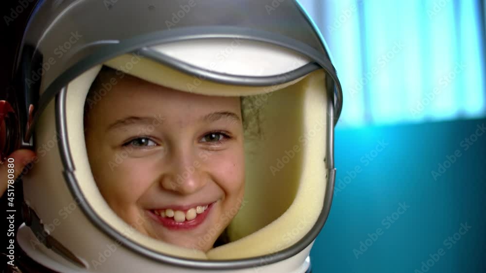 Child plays at home in an astronaut,portrait funny of a little girl 8-9 years old in a toy space helmet,smiling child looking at camera,close-up,pilot traveling into space.Concept of a happy childhood