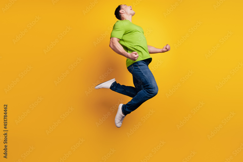 Portrait of crazy astonsihed sporty guy jump rejoice on yellow wall Portrait of crazy astonsihed sporty guy jump rejoice on yellow wall