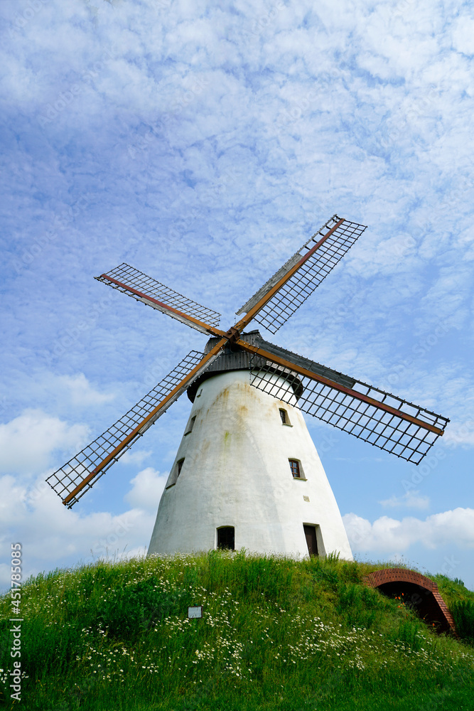 Old windmill near Veltheim, North Rhine Westphalia. White plaster and a wooden wind turbine. Blue sky in the background.