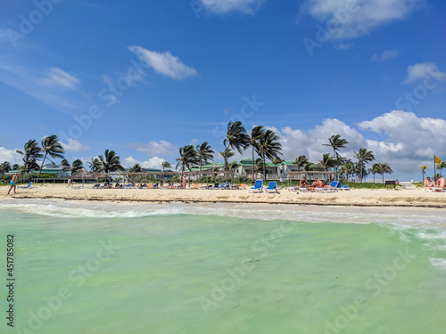 Cayo Coco, Cuba, May 16, 2021: Nice view of the sandy beach with turquoise water and palm trees. People are resting by the ocean.