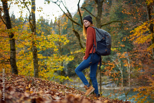 woman with a backpack walks in the autumn forest yellow leaves nature
