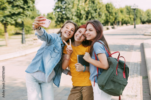 Three charming friends take selfies with their phone on the way to school. The concept of friendship. Education, training, back to school