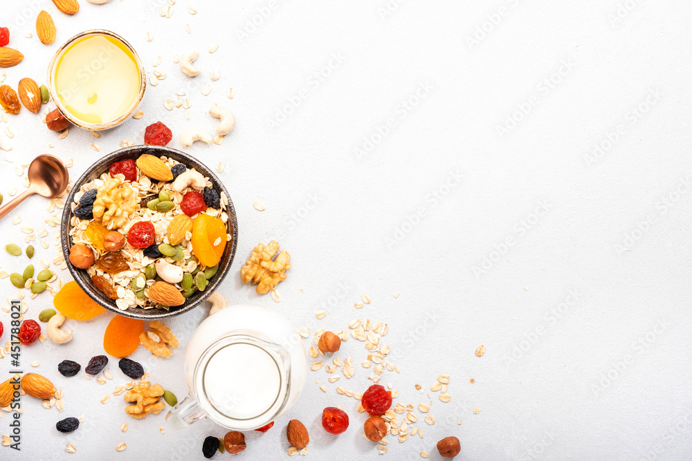 Muesli bowl and ingredients for healthy breakfast. Granola, nuts, dried fruits, flakes, honey and greek yogurt on white table copy space Muesli bowl and ingredients for healthy breakfast. Granola, nuts, dried fruits, flakes, honey and greek yogurt on white table copy space