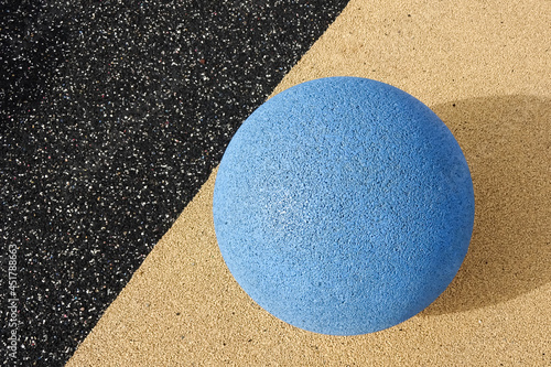 Close up of blue color stone grain textured ball in the center of yellow and asphalt background. Reidi tee street, Tallinn, Estonia.